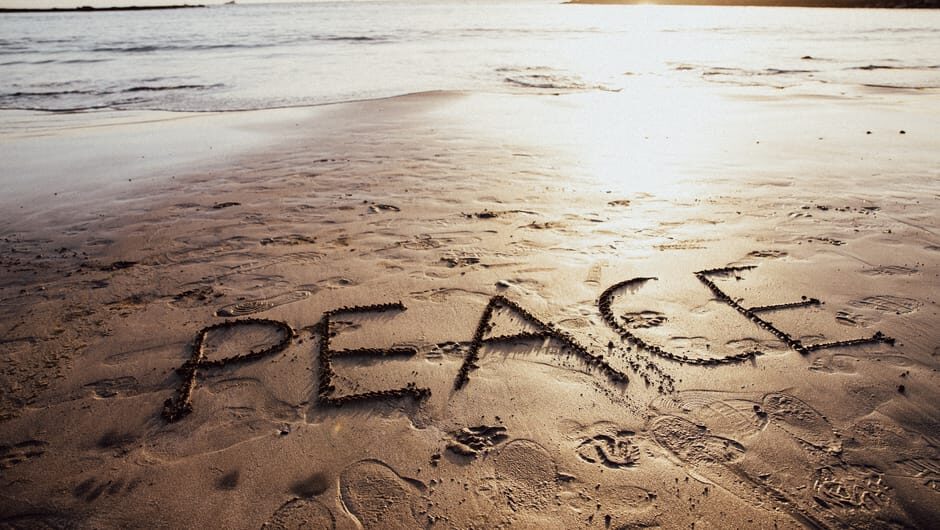 Peace written on a tranquil beach at sunset in the Canary Islands symbolizing tranquility and unity.
